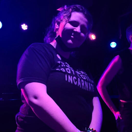 Barclay standing on a stage, smiling down at the camera.